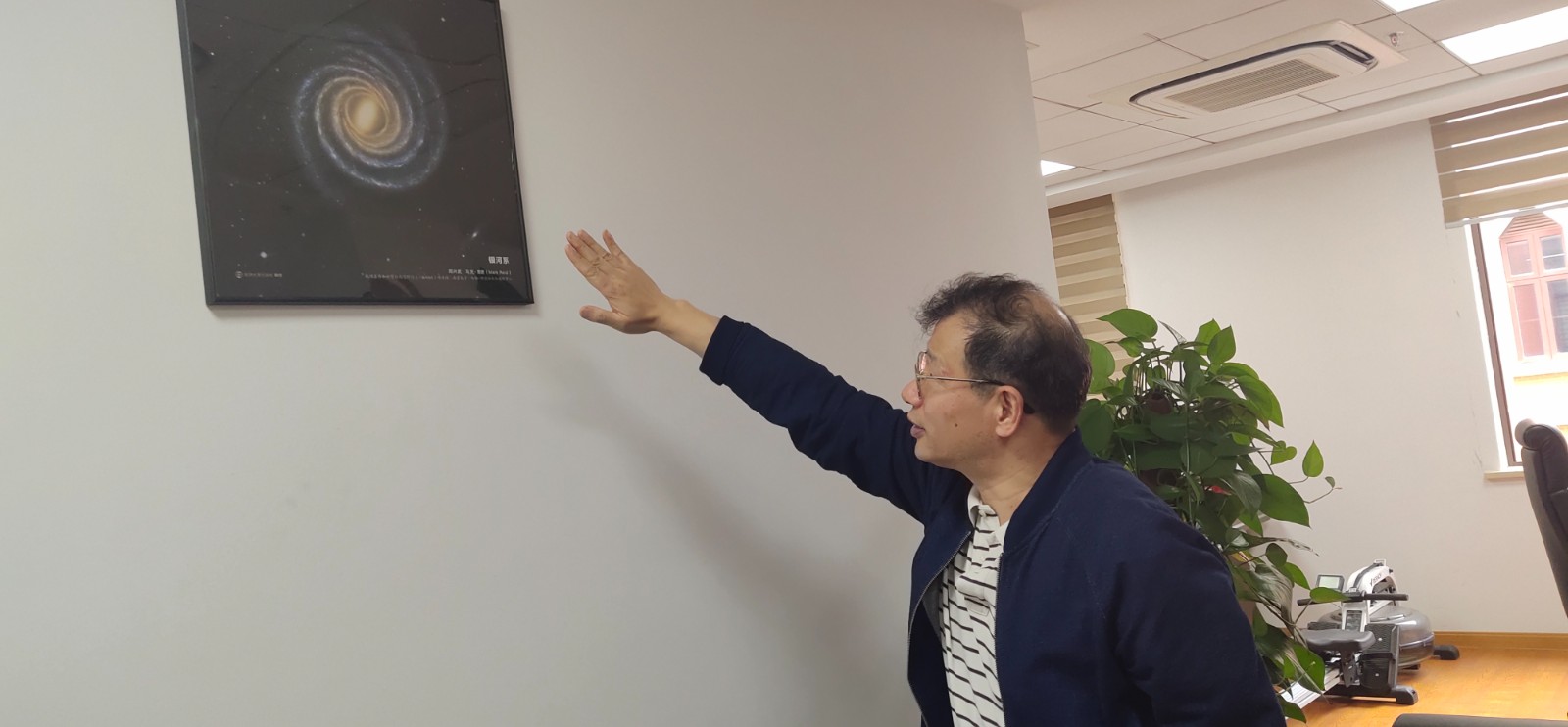 景益鹏院士正在介绍办公室墙上挂着的星系图.jpg